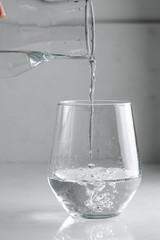 water is poured into a glass from a decanter