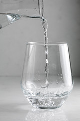 water is poured into a glass from a decanter
