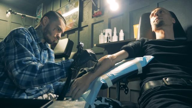 Handicapped person getting a new tattoo on a prosthetic hand.