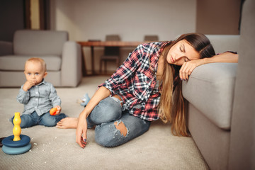 Obraz premium Little kid playing on the floor, mother sleeps