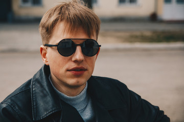 Portrait of a guy in round sunglasses and leather jacket