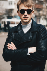 Portrait of a guy in round sunglasses and leather jacket