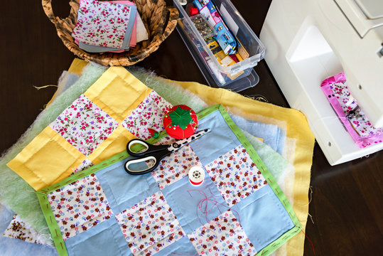 Sewing of handmade patchwork placemats with scissors, pool of threads and pin cushion