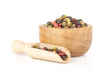 Lot of whole peppercorns of four colors with wooden bowl and wooden scoop isolated on white background