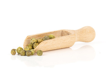 Lot of whole peppercorns of four colors with wooden scoop isolated on white background