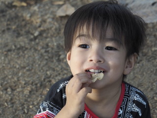 The boy is eating a crispy snack happily.