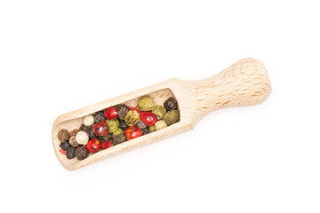 Lot of whole peppercorns of four colors with wooden scoop flatlay isolated on white background