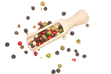 Lot of whole peppercorns of four colors with wooden scoop flatlay isolated on white background