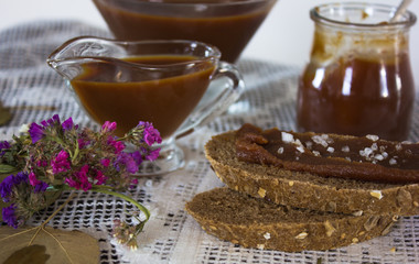 Homemade salted caramel sauce for christmas dessert in jar on rustic wooden table background. Copy space.