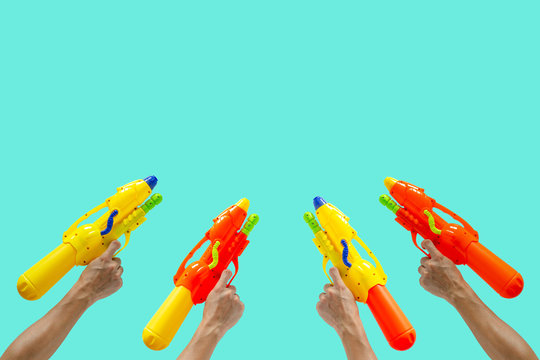 Hands Holding Plastic Water Gun Ready To Fight For Water Or Songkran Festival Which Celebrate In Thailand Summer Time On April With Sapphire Color Background.