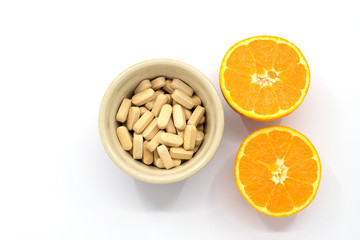 pot of vitamin c tablets with an orange cut in half