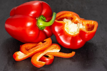 Group of one whole one half four slices of bulgarian red bell pepper on grey stone