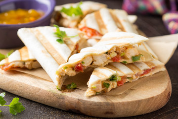 Mexican quesadilla with chicken, tomatoes, cheese and grilled sauce. Tasty snack in a pellet, healthy food