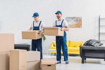 two movers transporting cardboard boxes in apartment