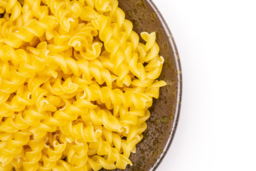 Lot of pieces of raw italitan yellow pasta torti in a grey ceramic bowl flatlay isolated on white background