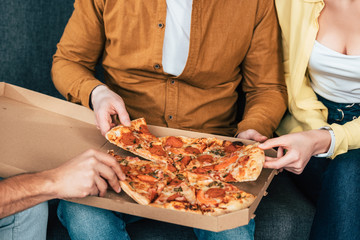  man in orange shirt holding pizza with friends in room