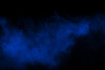 Blue color powder explosion cloud on black background.Closeup of Blue dust particles exhale on dark background.