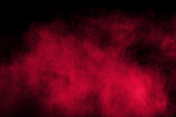Red color powder explosion on black background.Freeze motion of red dust particles splashing.
