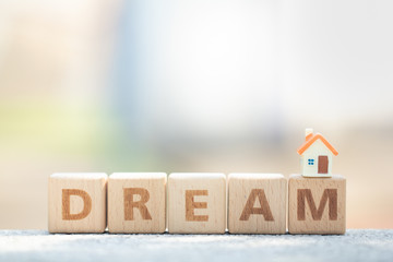 Miniature house model on wooden block text dream. Business, finance, and saving money for dream house concept