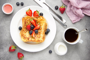French toast with berries (blueberries, strawberries) and sauce, traditional sweet dessert of bread...