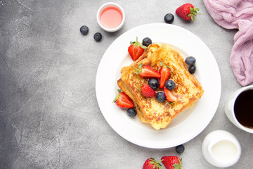 French toast with berries (blueberries, strawberries) and sauce, traditional sweet dessert of bread...
