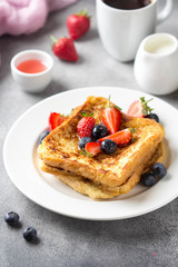 French toast with berries (blueberries, strawberries) and sauce, traditional sweet dessert of bread...
