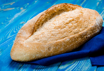 Whole loaf bread with crisp on wooden background top view