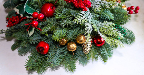 Christmas composition of pine branches, golden Christmas decorations, red berries and artificial snow.