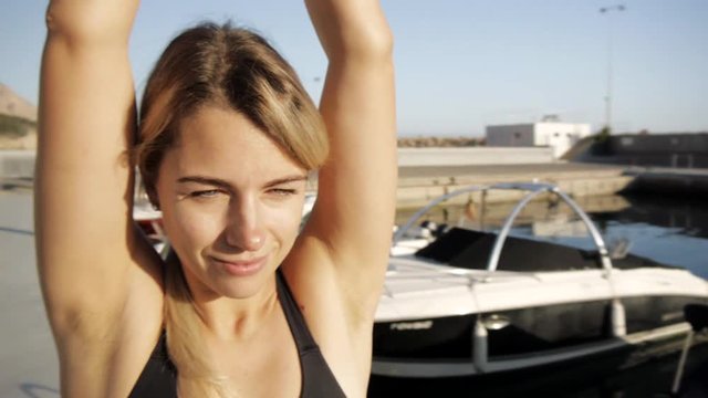 Young women doing exercises at sea port. Spinning shot of fit attractive caucasian woman practicing yoga standing with hands above the head
