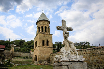 Obraz premium Church tower and tombstone with a cross and two headless angels. Religion, Georgia, Mtskheta. Temple. Monument, statue. Architecture
