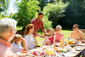leisure, holidays and people concept - happy family having festive dinner or barbecue party at...