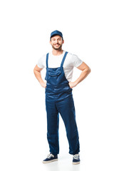 handsome smiling mover in uniform with hands akimbo looking at camera isolated on white