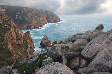 Fototapeta na wymiar Seascape, rocky coast of the Atlantic Ocean, near Cape Roca in Portugal in the spring cloudy weather