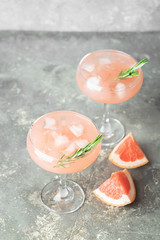 Drink grapefruit rosemary juice and ice glass goblets on a light gray concrete background. A refreshing summer cocktail.