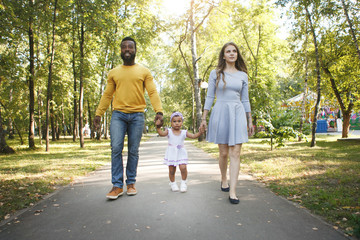 Obraz premium Dark-skinned girl, dad and mom in the park.