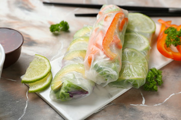 Tasty spring rolls on color table