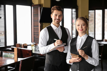 Young waiters with notebooks in restaurant