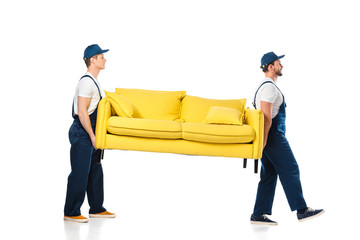 side view of two movers transporting yellow sofa on white