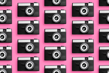 Plastic photo cameras organized in a row over pink background
