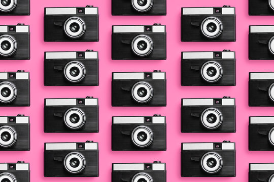 Plastic photo cameras organized in a row over pink background