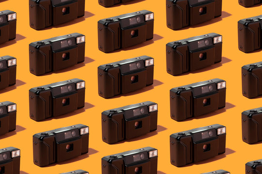 Plastic photo cameras organized in a row over orange background