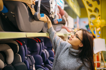 Pregnant woman choosing child car seat in store