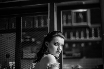 Model posing in a white long wedding dress indoors by the window. Advertising of wedding dresses