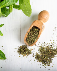 Dried peppermint in a white bowl and a bunch of fresh mint, on wooden background. Food background. © ozgur