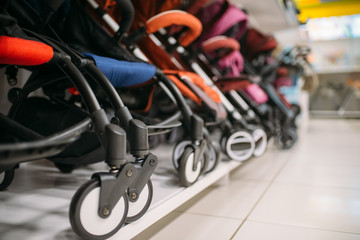 Row of baby strollers on shelf in store, nobody