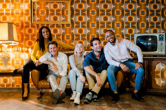 Group of smiling people sitting on couch in vintage living room