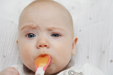 Beautiful Lovely five-month baby girl eating with a spoon. Healthy food. Maternal care. Childcare. Close-up.