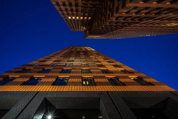 Fototapeten View of high rise brick building on blue clear avond sky background, Business concept of future architecture, looking up to the night sky on the top of building. © fotografiecor