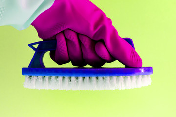 Hand in pink rubber latex glove with blue Handheld floor brush cleaning in on yellow background