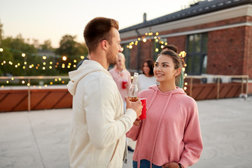 leisure, celebration and people concept - happy friends with non alcoholic drinks at rooftop party in evening